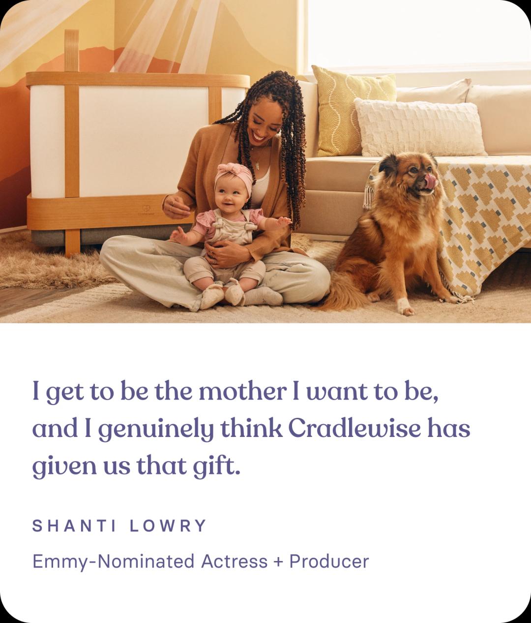 Shanti Lowry, who's an Emmy Nominated Actress + Producer and a satisfied Cradlewise customer, smiling as she holds her baby next to the Cradlewise smart crib, highlighting her positive review and experience with the crib’s features and benefits.